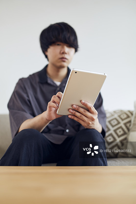 男人在沙发上操作平板电脑图片素材