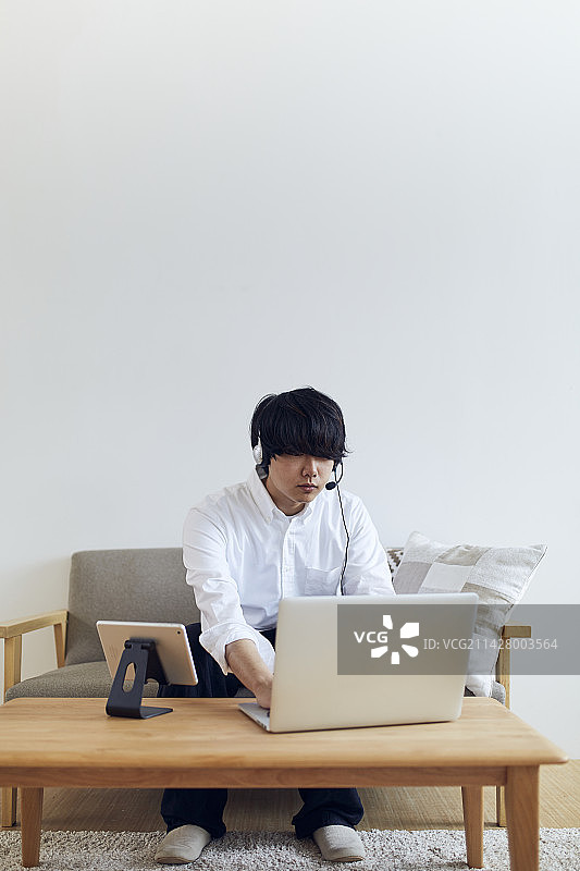 在客厅使用电脑和平板及对讲机的男人图片素材