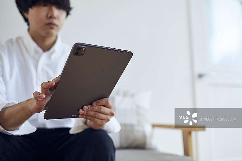 男人在沙发上操作平板电脑图片素材