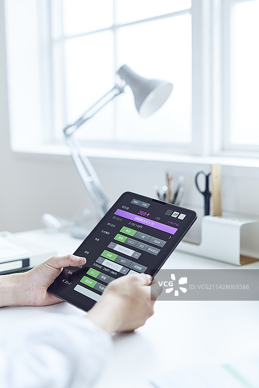 在办公桌旁用平板电脑下单购买股票图片素材