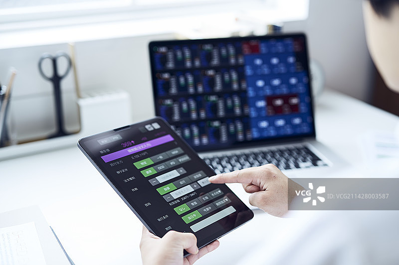 男人在办公桌前用平板电脑下单，同时查看电脑图片素材