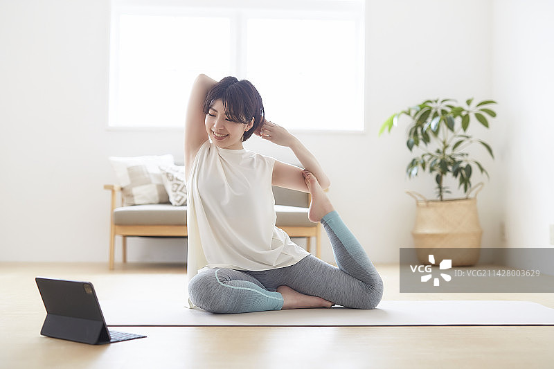 在室内地板上看笔记本电脑做瑜伽的女人图片素材