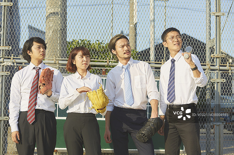 四名男女身穿西装，带着棒球装备排成一列图片素材