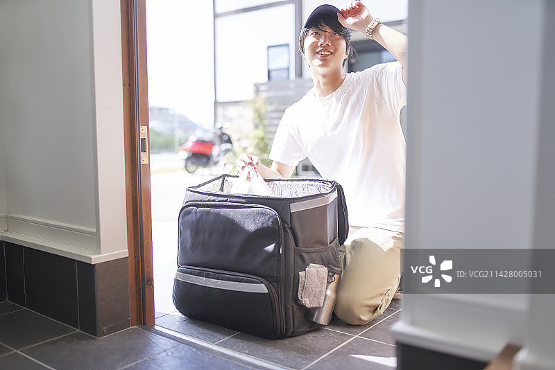 外卖员在前门从背包中取出物品图片素材