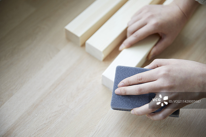 女人用手锉削一块方形木头图片素材