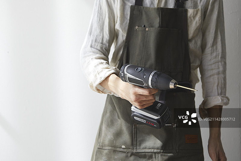 戴着围裙，手持电动螺丝刀的男人图片素材