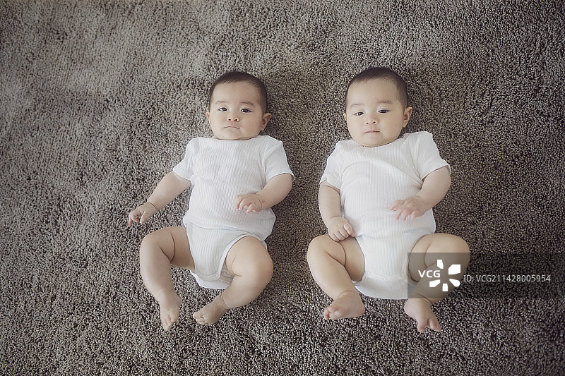 躺在灰色地毯上的双胞胎婴儿图片素材