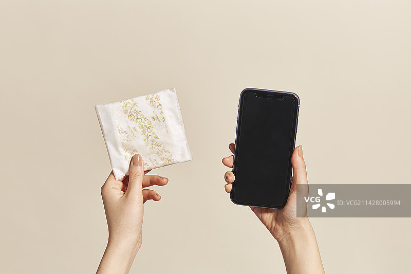 女人手持卫生巾和智能手机图片素材
