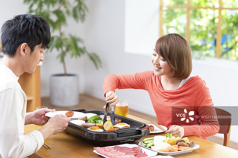 20多岁的情侣吃烤肉，喝生啤图片素材