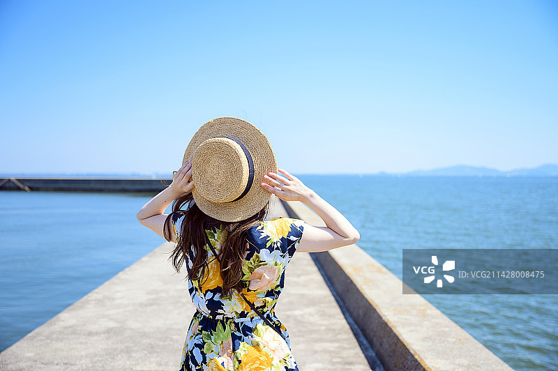 女人前往海边度假胜地，沿着海港防波堤散步图片素材