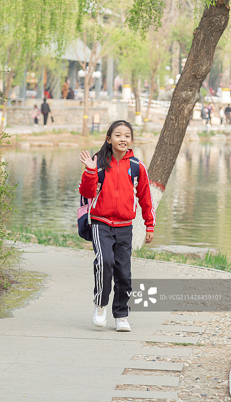 背书包穿校服的小学生走在户外的路上图片素材