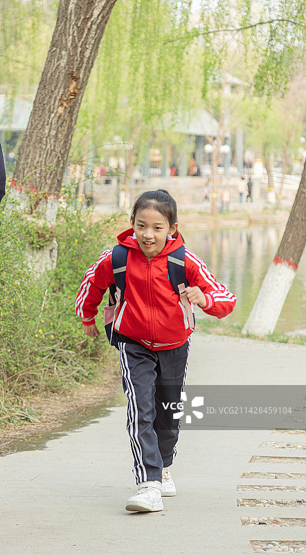 背书包穿校服的小学生走在户外的路上图片素材