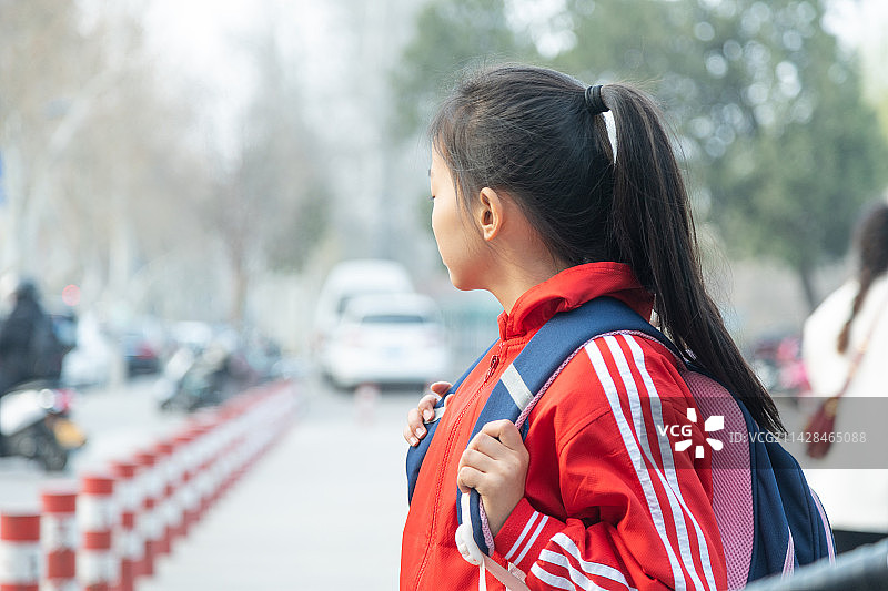 背着书包走在城市街头的小女孩图片素材