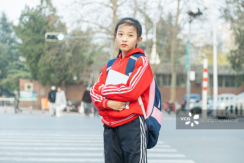 怀抱着书站在城市街道的小学生图片素材