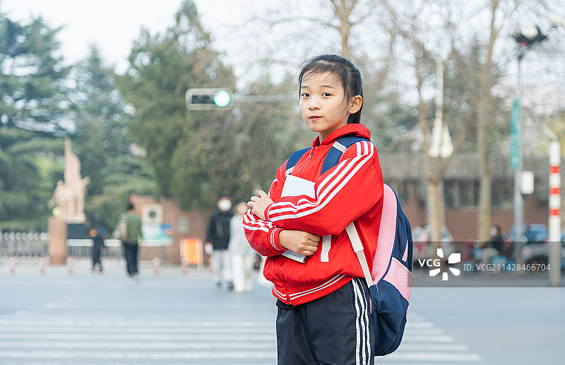 怀抱着书站在城市街道的小学生图片素材