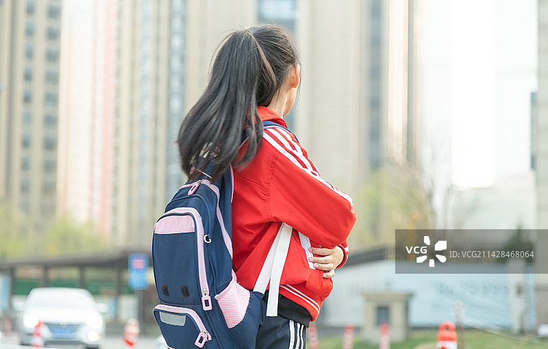 城市背景前抱着书的小女孩肖像图片素材