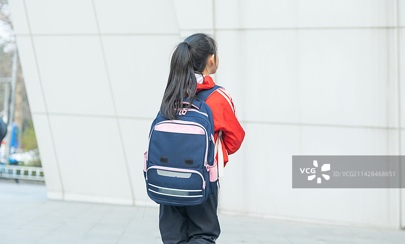 走在城市中背着书包的小学生背影图片素材