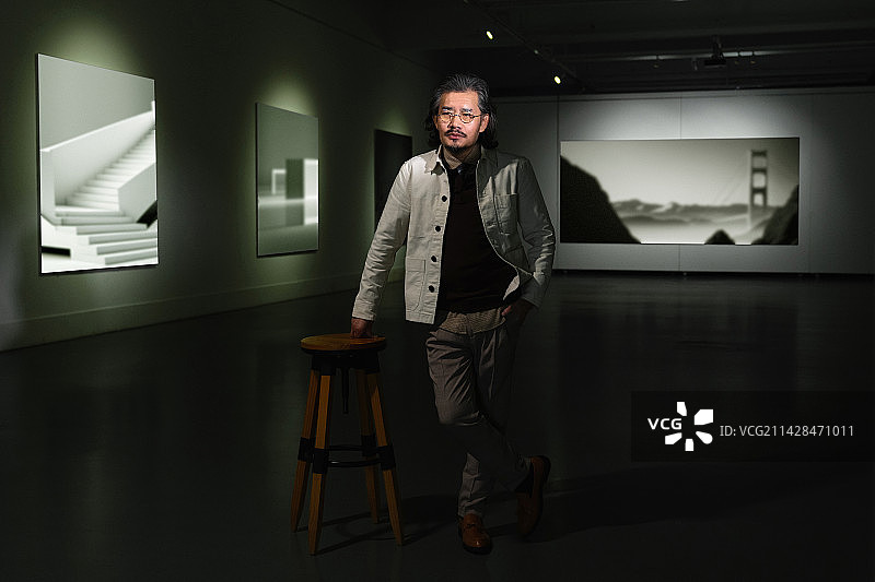 画展上的老艺术家扶着高凳图片素材