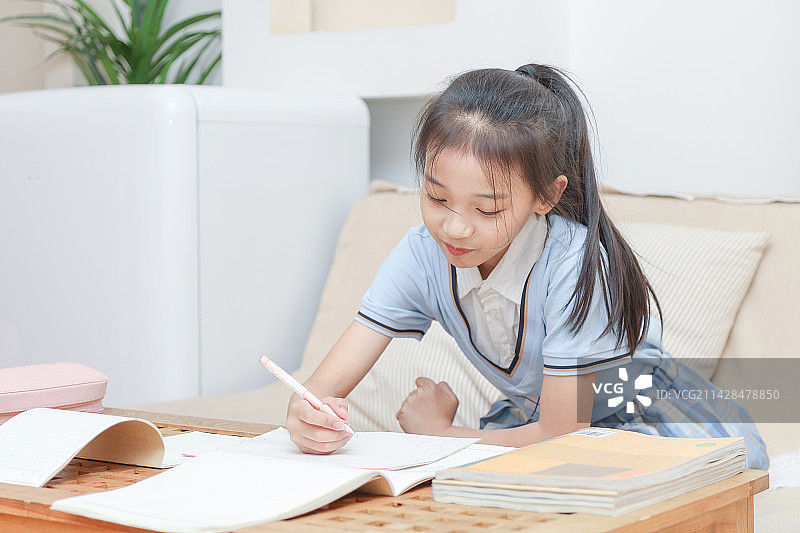 客厅里正在写作业的小女孩肖像特写图片素材