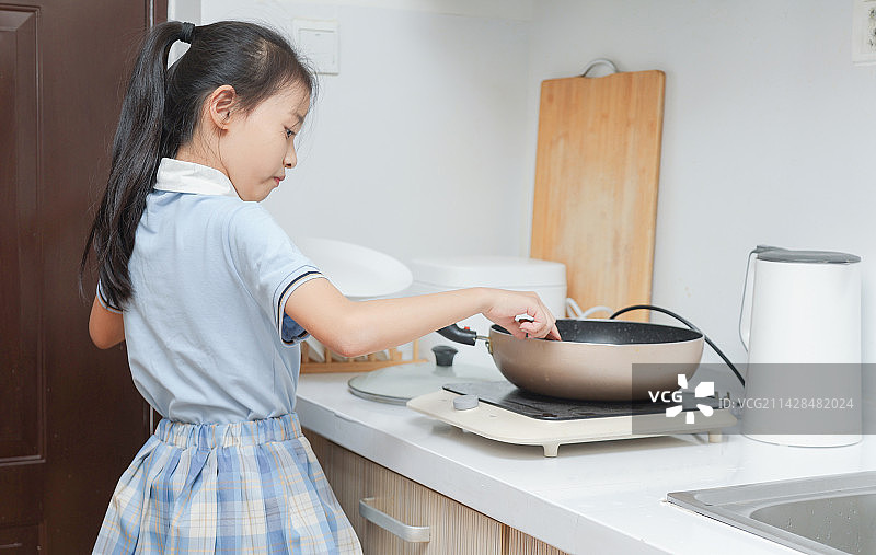 厨房里拿着餐具做饭的小女孩图片素材