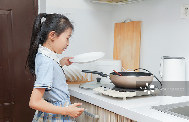 厨房里拿着餐具做饭的小女孩图片素材