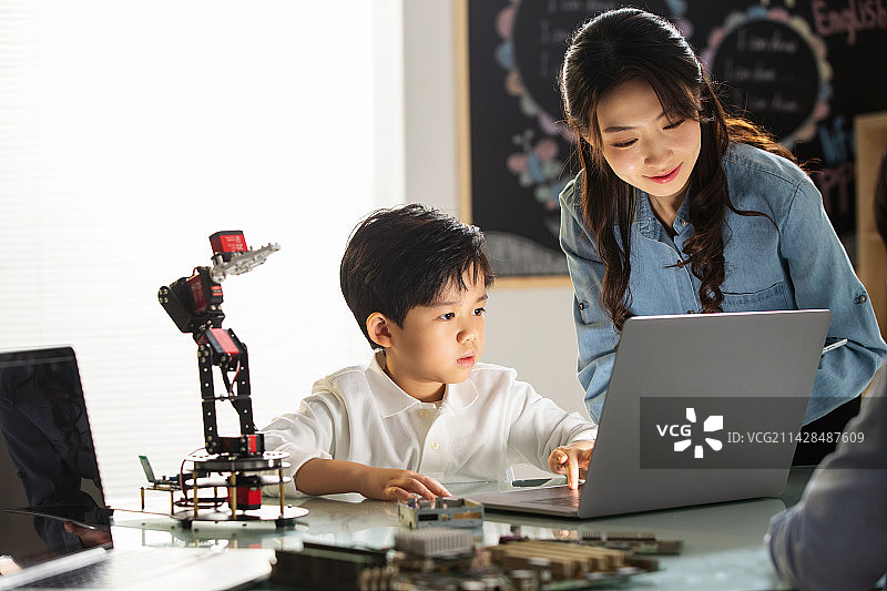 老师教小学生学习机器人编程图片素材