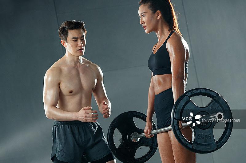 青年女人在教练的指导下举重训练图片素材