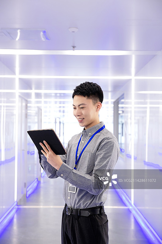 走廊里技术人员拿着平板电脑图片素材