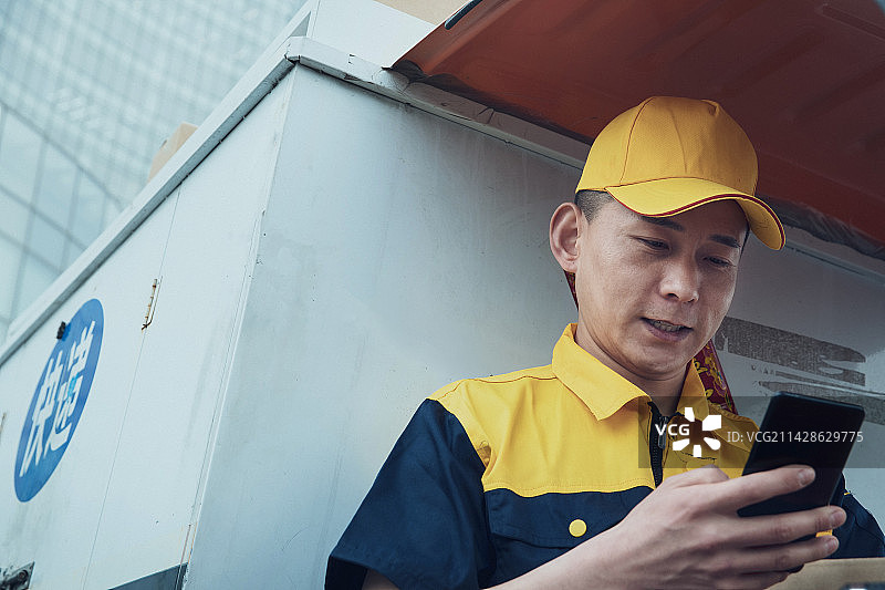 拿着包裹的快递员查看手机订单图片素材