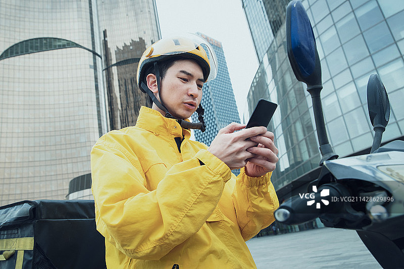 送餐的青年外卖员发短信图片素材