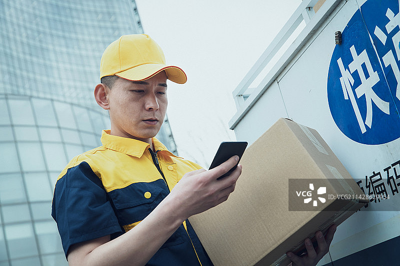 拿着包裹的快递员查看手机订单图片素材
