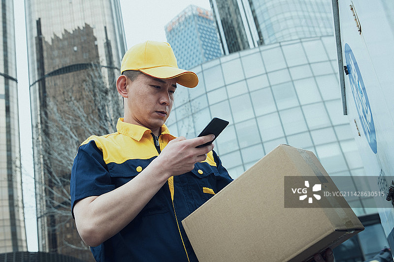 拿着包裹的快递员查看手机订单图片素材