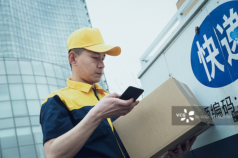 拿着包裹的快递员查看手机订单图片素材