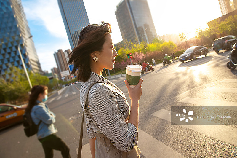 青年女人拿着饮料走在马路上图片素材