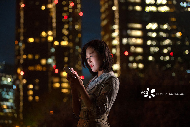晚上在户外看手机的商务女白领图片素材