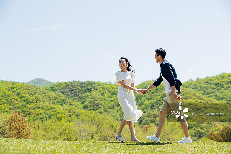 手牵手在郊外旅行的青年情侣图片素材