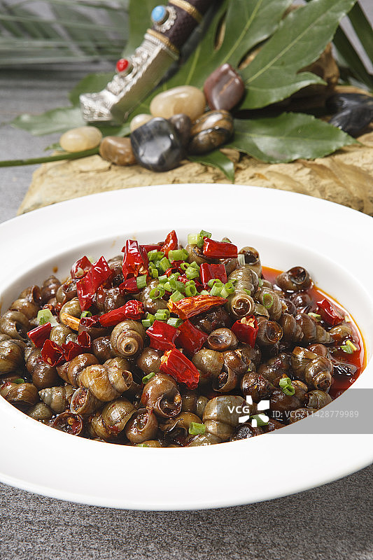 白色瓷盘装的香辣炒田螺图片素材