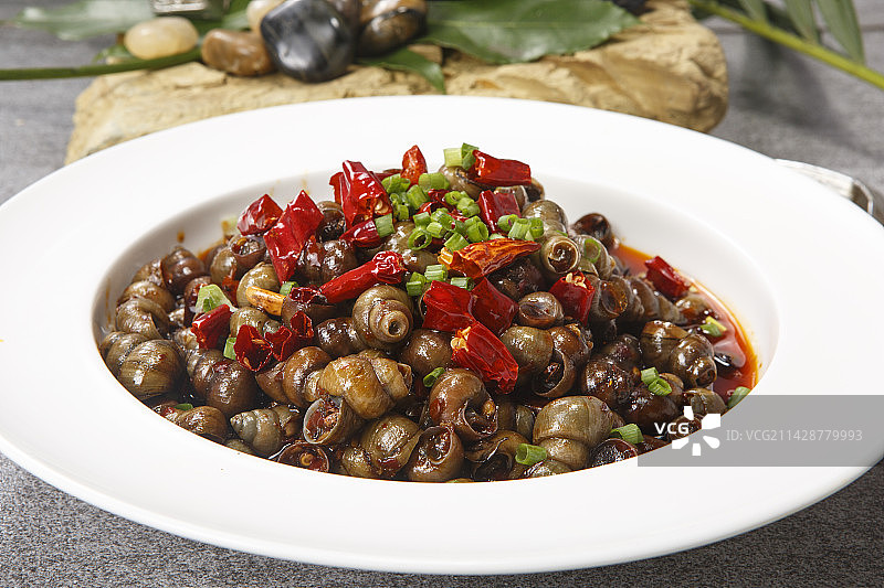 白色瓷盘装的香辣炒田螺图片素材