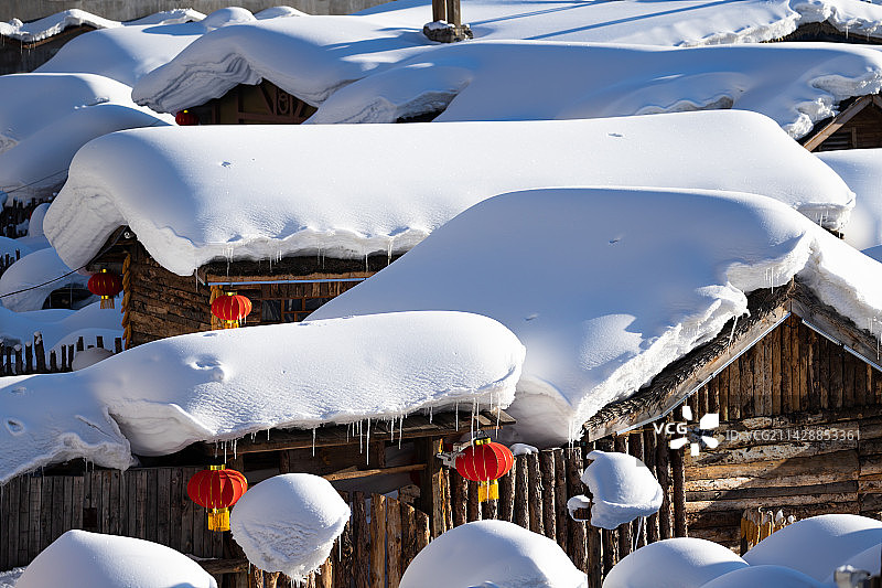 冬天里晴朗天气的清晨，黑龙江中国雪乡景区，雪韵大街两旁的农家院屋顶上厚厚的积雪。图片素材
