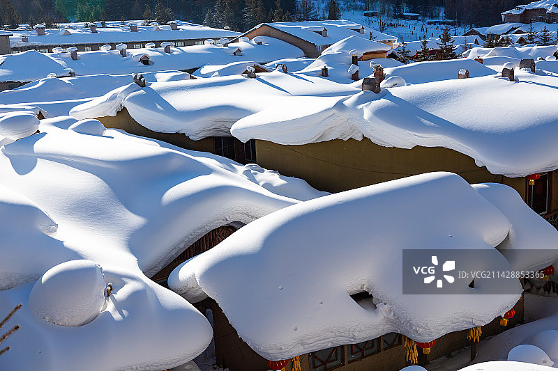 冬天里晴朗天气的清晨，黑龙江中国雪乡景区，雪韵大街两旁的农家院屋顶上厚厚的积雪。图片素材