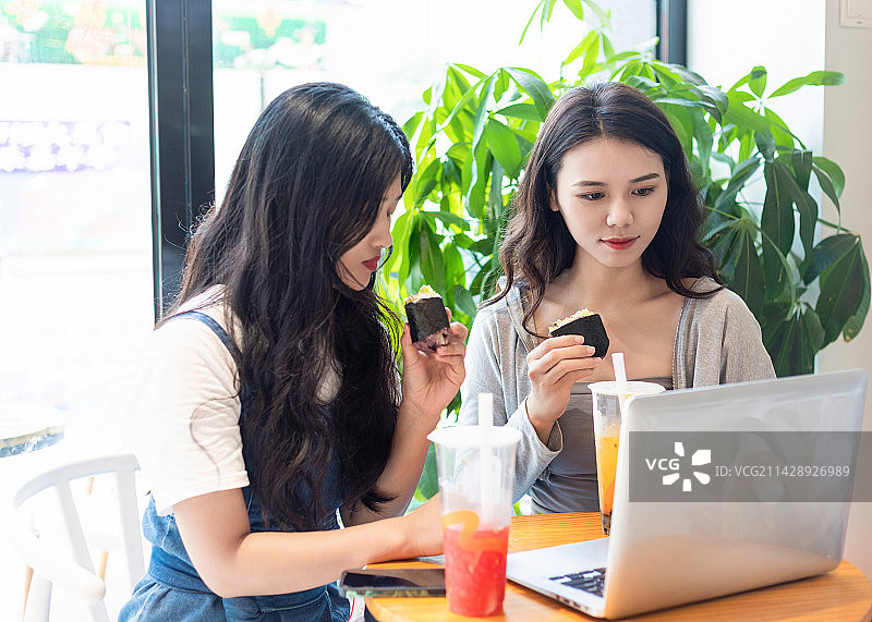奶茶店里两名中国美女边吃下午茶边办公图片素材