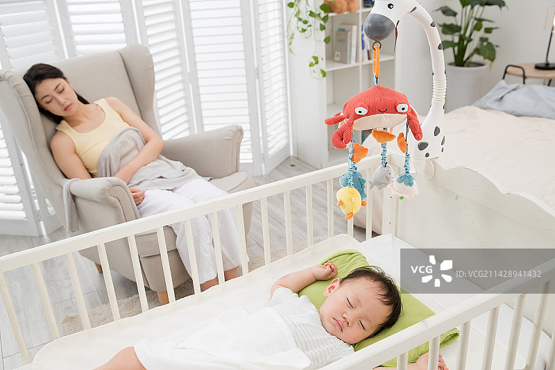 年轻妈妈陪伴睡觉的宝宝图片素材