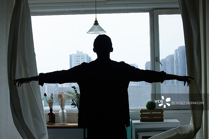 青年男人打开窗帘往外看图片素材