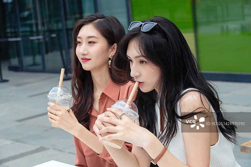 快乐闺蜜坐在户外喝奶茶图片素材