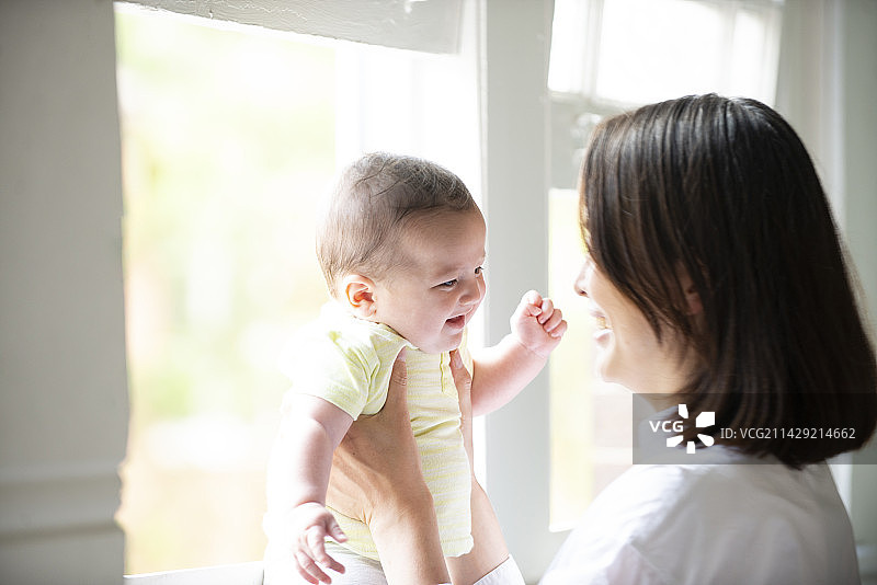 母亲在窗边给宝宝喂奶图片素材