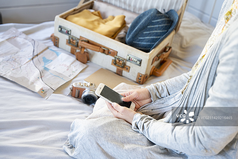 女人在床上为旅行做准备时看手机图片素材
