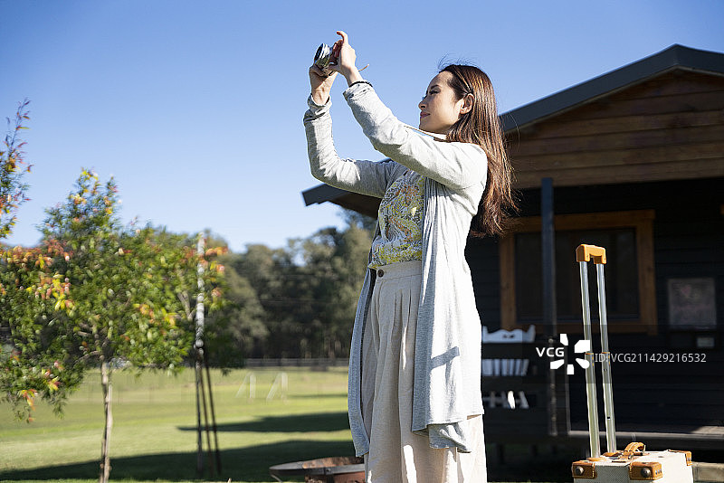 在小屋前拍照的女人图片素材