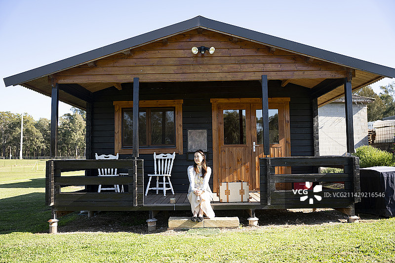 在小屋门廊上放松的女人图片素材