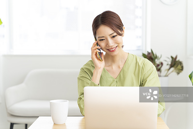 看着电脑打电话的女人图片素材