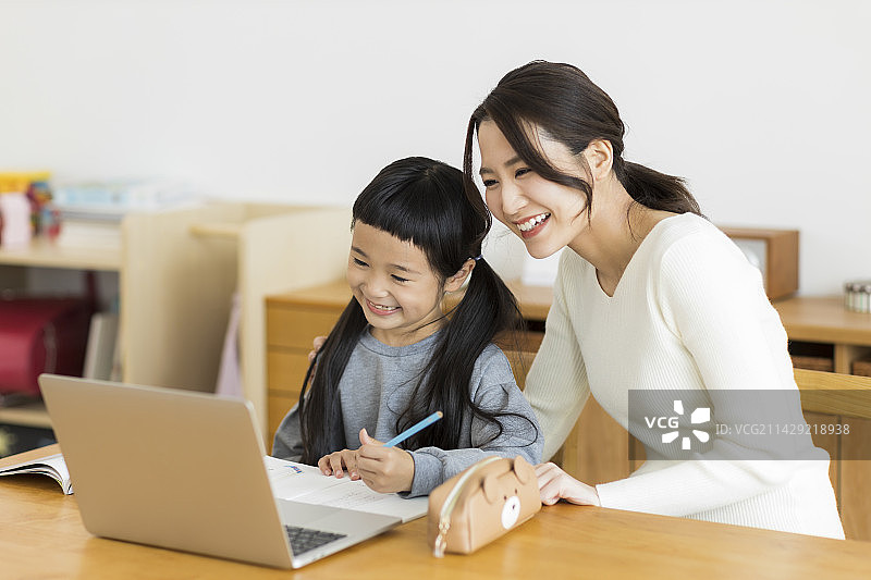 女孩和她的母亲在电脑上学习网课图片素材